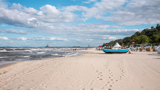 Heringsdorf, Mecklenburg-West Pomerania Germany - September 4, 2022: View of the pier on the Baltic Sea beach with a fisher boat in Heringsdorf during the day. Strong waves under a cloudy sky.