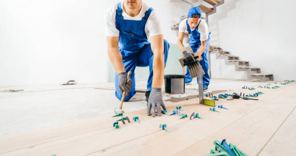 istock Two workers in a special uniform laying tiles with tile leveling system and laser level on the floor in a new house 1420928946
