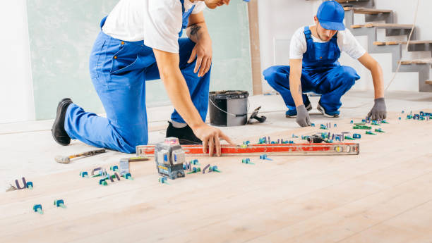 istock Two workers in a special uniform laying tiles with tile leveling system and laser level on the floor in a new house 1420929081
