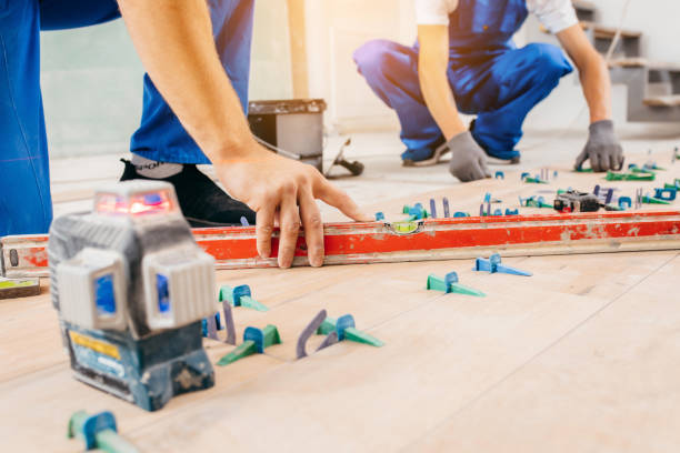 istock Two workers in a special uniform laying tiles with tile leveling system and laser level on the floor in a new house 1420929092