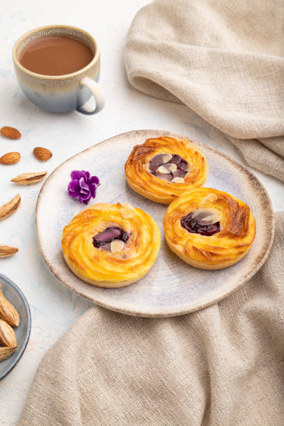 istock Small cheesecakes with jam and almonds with cup of coffee on a white concrete background. Side view. 1420929678