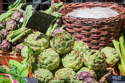 Bunch of artichokes are stacked on top of each other.