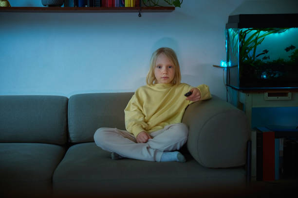 istock Cute girl watching television alone at night at home 1420930341
