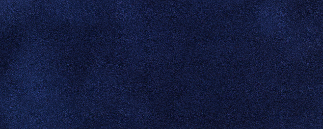 Navy blue suede fabric background, macro. Velvet matte texture of dark denim nubuck textile. Structure of fleecy backdrop, closeup.