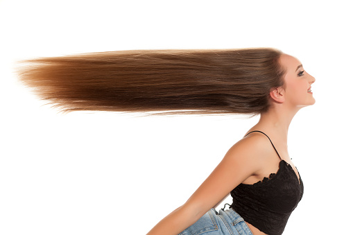 Young smiling woman with very long flying hair on white background