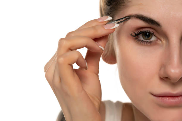 istock Young woman plucking eyebrows with tweezers close up 1420935735