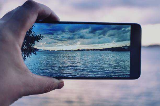 istock Cropped hand holding mobile phone against sea 1420937191