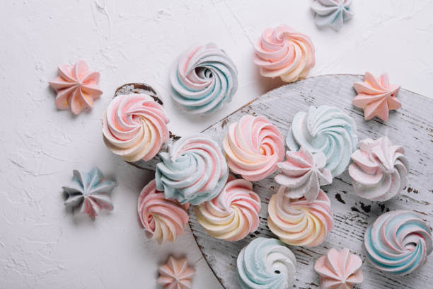 Multicolored meringue on wooden tray top view
