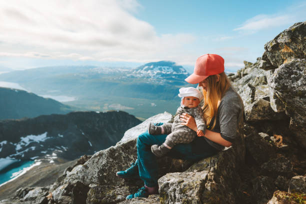 Mother and baby hiking together in mountains family travel outdoor active healthy lifestyle woman with child enjoying view vacations in Norway stock photo
