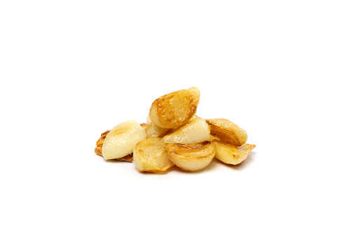 Fried garlic cloves pile closeup isolated. Roasted grilled garlic clove group on white background side view