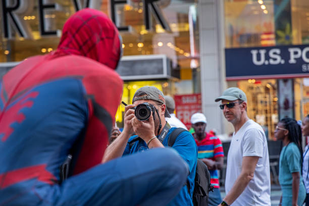 Times Square, Manhattan, New York, NY, USA - July 10th 2022: Man taking a portrait photo of one of the Spiderman impersonators at Times Square