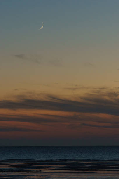 istock Crescent moon on twilight sky over beach with sea in evening with colorful sunlight after sunset 1420949055