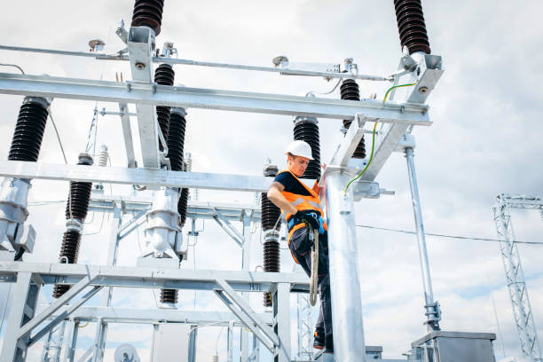 istock Electrician in protective helmet working on high voltage power lines. Highly skilled workmen servicing the electricity grid. Modern power station with power towers 1420952756