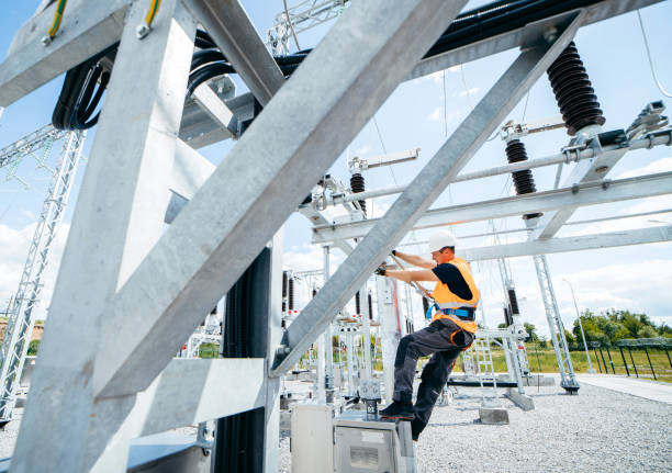 istock Electrician in protective helmet working on high voltage power lines. Highly skilled workmen servicing the electricity grid. Modern power station with power towers 1420952782