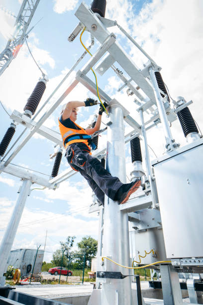 istock Electrician in protective helmet working on high voltage power lines. Highly skilled workmen servicing the electricity grid. Modern power station with power towers 1420952811