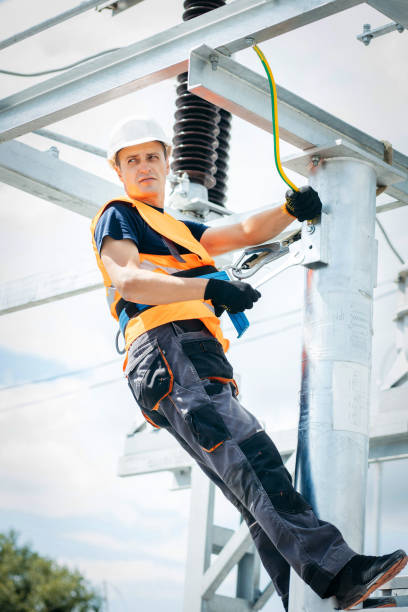 istock Electrician in protective helmet working on high voltage power lines. Highly skilled workmen servicing the electricity grid. Modern power station with power towers 1420952888