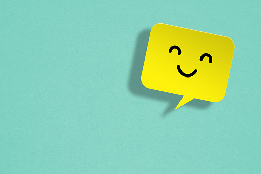 White chat bubble with happy face emoticon over grey background. Horizontal composition with copy space and clipping path. Great use for online messaging concepts.