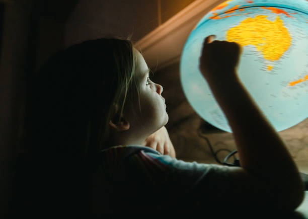 istock Little Girl Looking at a Globe at Night 1420957774