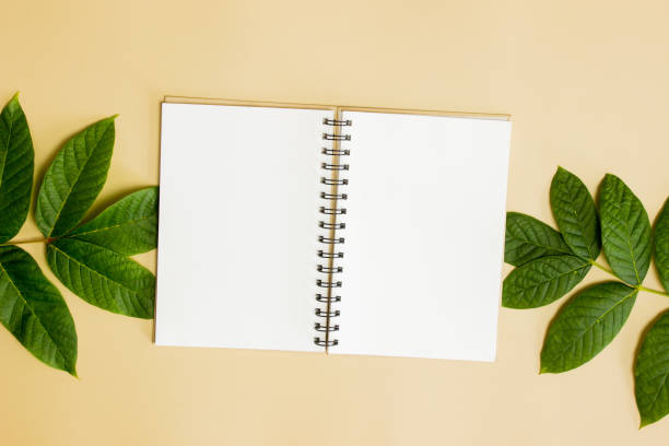 istock Notebook with green leaves over the brown background. 1420957789