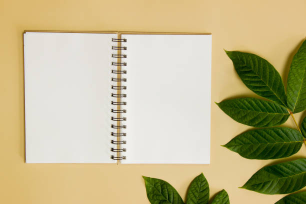 istock Notebook with green leaves over the brown background. 1420957826