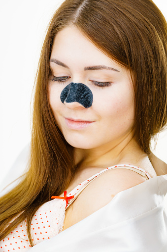 Woman with charcoal strip on nose, remover mask for blackheads cleaning. Girl taking care of skin complexion. Beauty treatment. Skincare.
