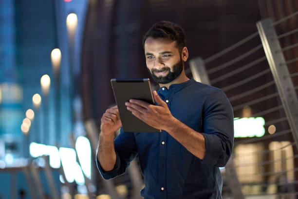 istock Professional indian business man using digital tablet outdoors in night city. 1420959426