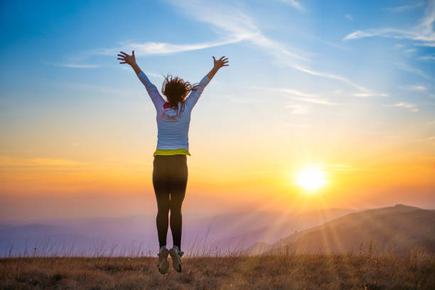 istock Young woman jumping at sunset mountains 1420970715
