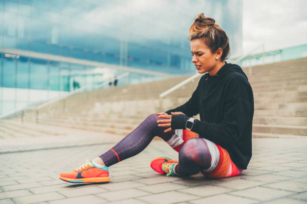 istock Sportswoman with broken leg sitting on ground 1420972885