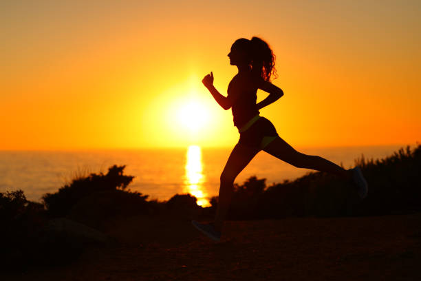 istock Silhouette of a runner running at sunset on the beach 1420973031