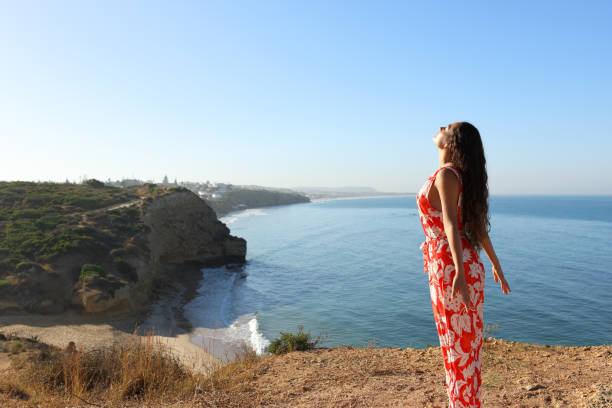 istock Woman breathing on a clif on the beach 1420973396