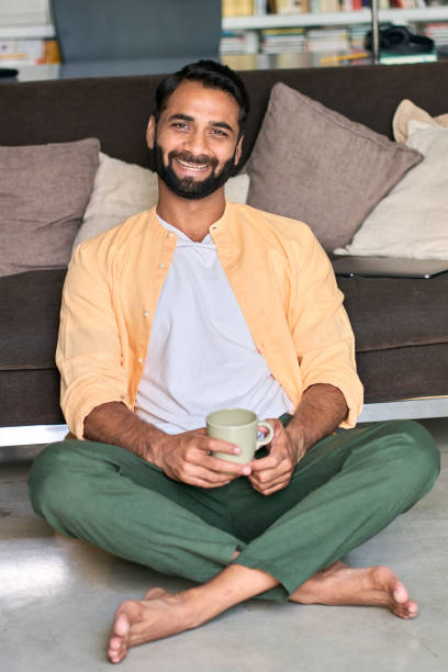 istock Happy indian man looking at camera drinking coffee at home. Vertical portrait 1420974991