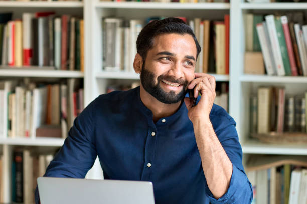 istock Happy indian business man working in office talking on phone making call. 1420975083