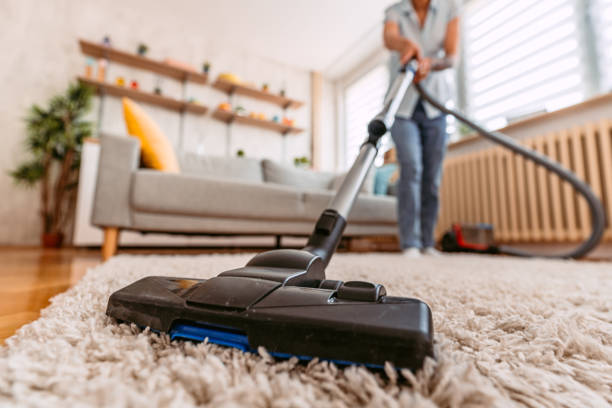 senior woman vacuuming her apartment - vacuum cleaner imagens e fotografias de stock