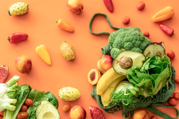 Fresh fruits and vegetables on a colored background, flat lay. Fresh fruits and vegetables in a green string bag on a colored background, flat lay. Artichoke stock pictures, royalty-free photos & images