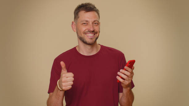 istock Handsome young man using smartphone show thumbs up like, positive feedback, recommends 5G connection 1420975623