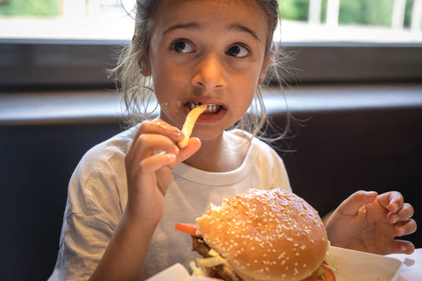 istock A little girl eats fast food in a cafe. 1420977433