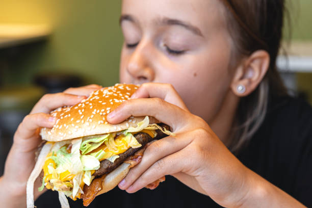 istock A little girl eats an appetizing burger, close-up. 1420977445
