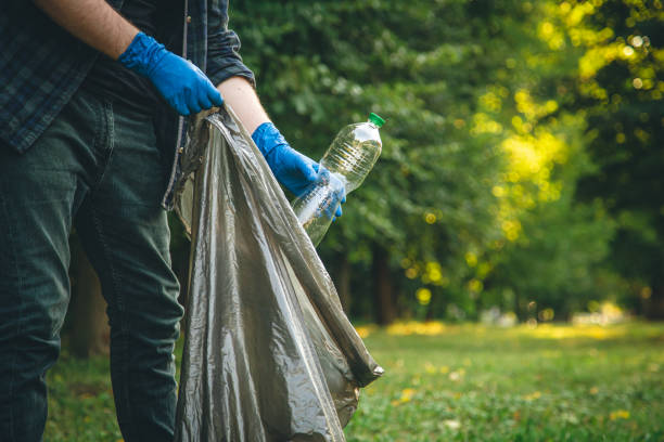 istock A man cleans up the forest, throws a bottle into a trash bag, close-up. 1420981151