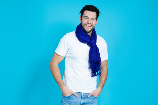 Positive Handsome Man Posing in White Shirt And Blue Scarf While Smiling And Looking Straight to Camera Over Blue Background.Horizontal Shot