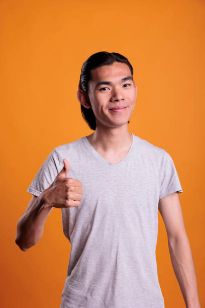 istock Young cheerful smiling asian man giving thumb up 1420983641