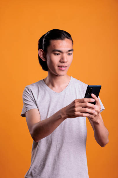 istock Young asian man typing message on smartphone 1420984192