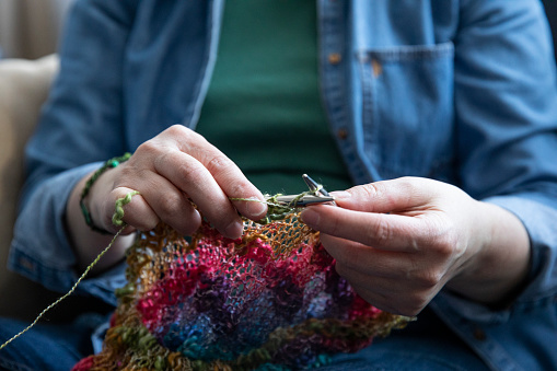Mature woman knitting wool at home