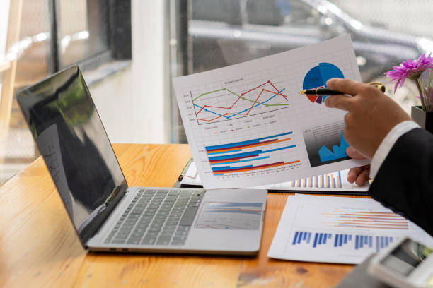 istock businessman holding pen with laptop graphing documents financial calculator deck for calculations and analysis 1420985502