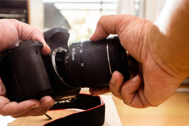 istock Photographer attaching a lens to a professional still camera. 1420990200