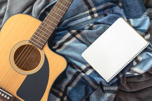 istock Acoustic guitar and notepad on a plaid background, top view. 1420992560