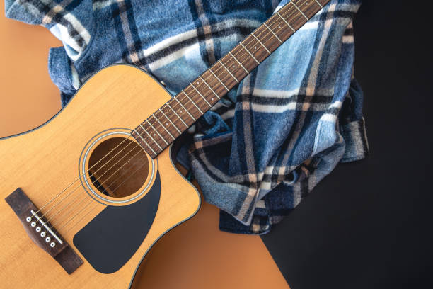 istock Acoustic guitar and checkered plaid on a colored background, top view. 1420992610