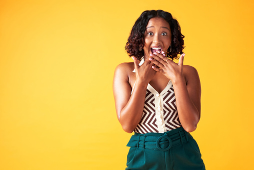 Mockup space and wow, surprise or gossip with a young woman in studio isolated against a yellow background. Portrait of a person saying omg at a sale, deal or announcement about discount news