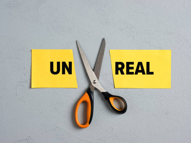 Goal achievement, realistic goals and potential, overcoming difficulties concept. Scissors Cutting off the word unreal and transforming into real. Goal achievement, realistic goals and potential, overcoming difficulties concept. real life stock pictures, royalty-free photos & images