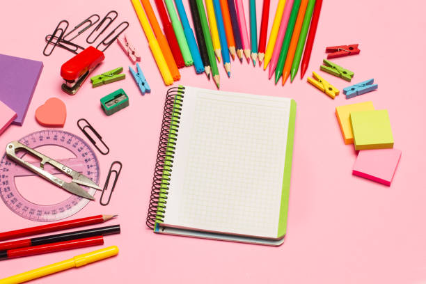 istock Blank open graph paper notebook and school utensils on a pink background 1421002892