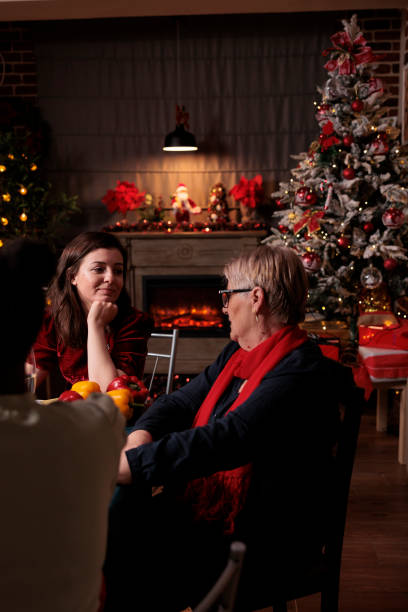 дочь разговаривает с мамой на рождественском праздничном ужине - senior adult winter senior women daughter стоковые фото и изображения